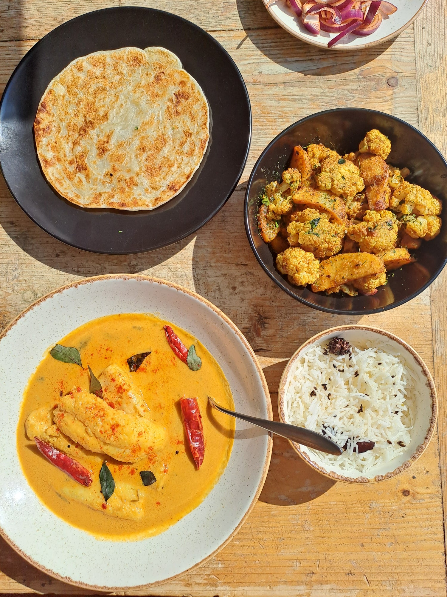 Home-cooked Indian meal spread - curry, aloo gobi, paratha and rice by Saakshis